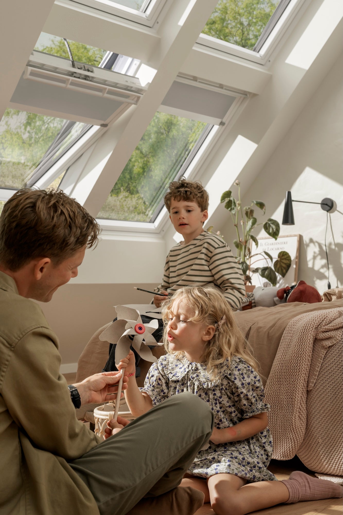 Man and two children sitting on a couch in a room with large windows.
