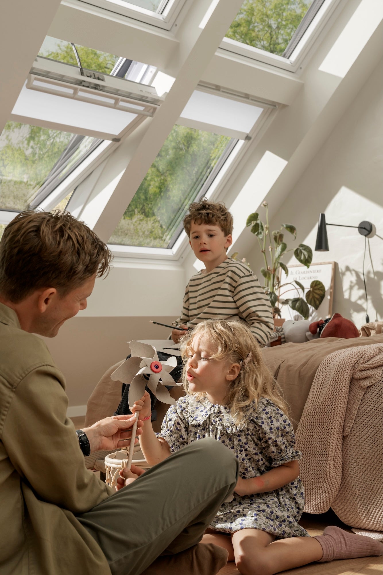Man and two children sitting on a couch in a room with skylights.