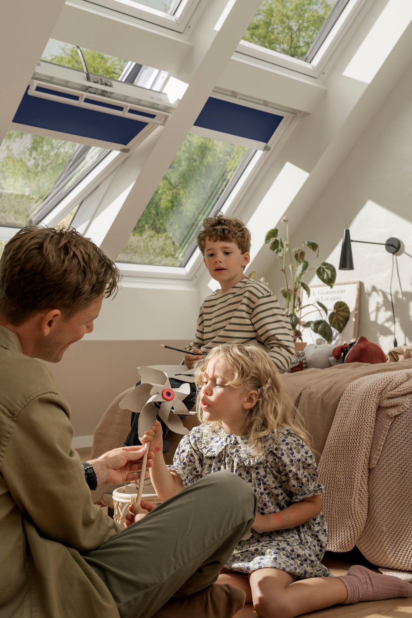 Man and two children sitting on a couch in a room with large windows.